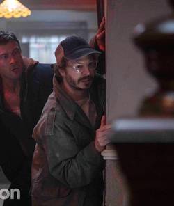 Michael Cera and Glen Powell peaking around a corner in The Running Man 2025